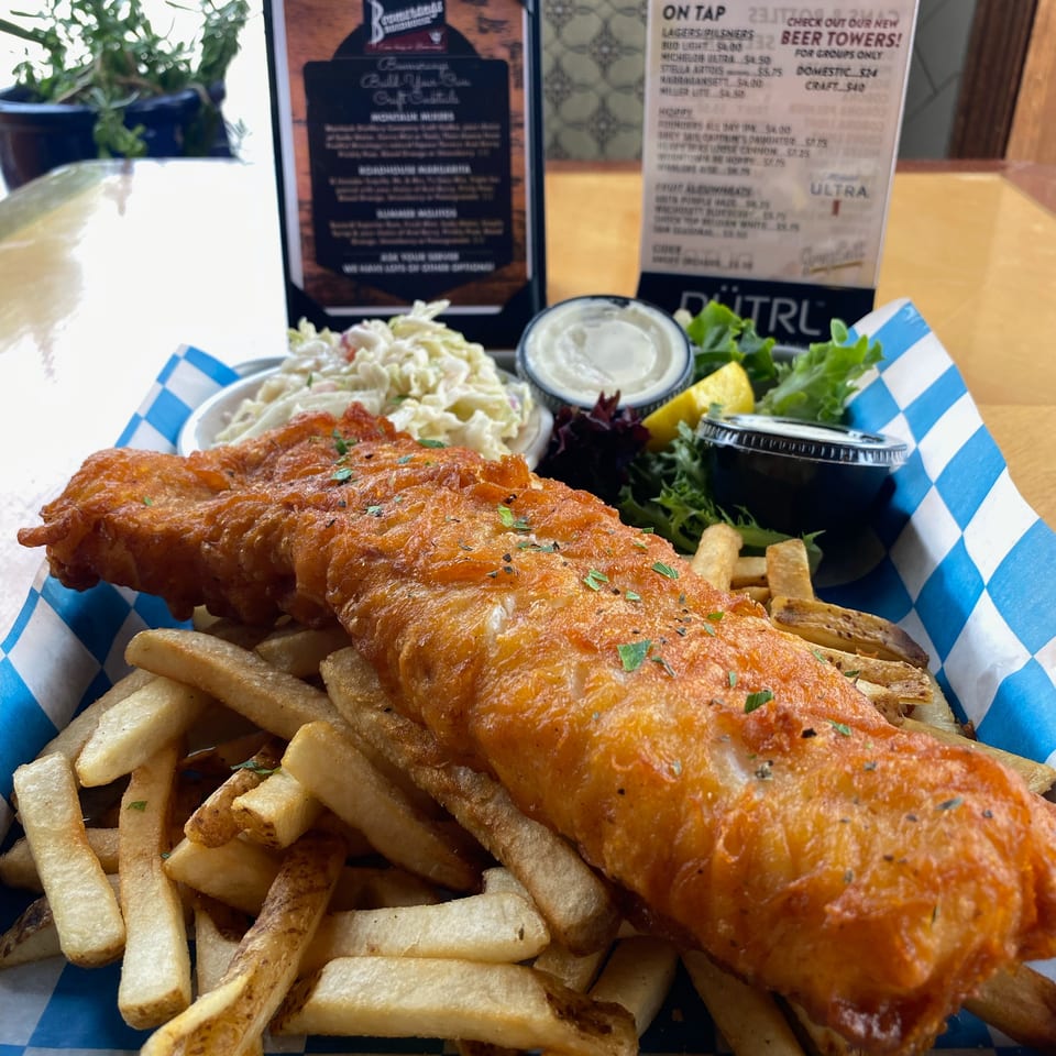 Crispy battered fish with fries, coleslaw, dipping sauce, lemon, and salad served at Boomerang's Roadhouse.